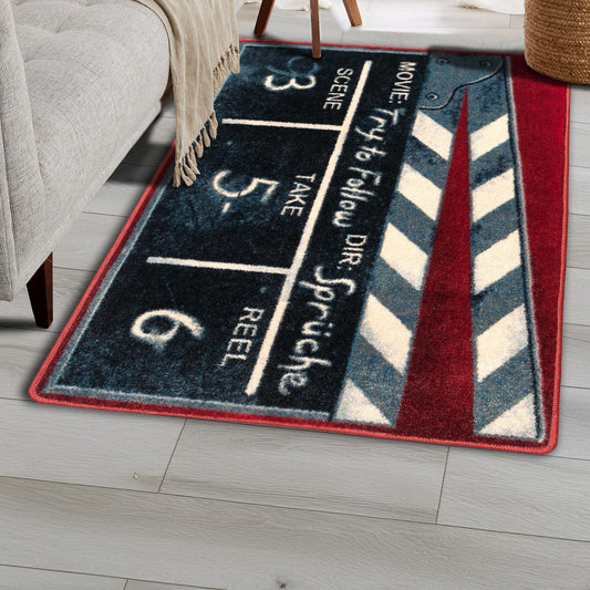 The Cue, Action Rug styled in a home setting beneath a sofa, showcasing its clapperboard design with bold cinematic details