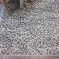 Load image into Gallery viewer, The Ghost Lynx Hide Rug styled in a cozy corner, showcasing its misty gray leopard print and suitability for reading nooks or stylish game rooms.