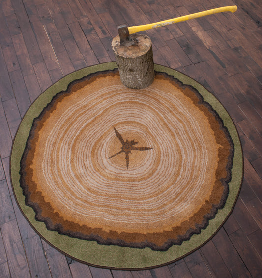 Round tree stump rug styled with axe and log on dark wood floors—rug adds rustic, nature-inspired texture to modern creative or game rooms.