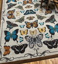 Load image into Gallery viewer, Detail of butterfly game room rug near wooden bench with leopard blanket—highlighting bold color and fine illustration details.