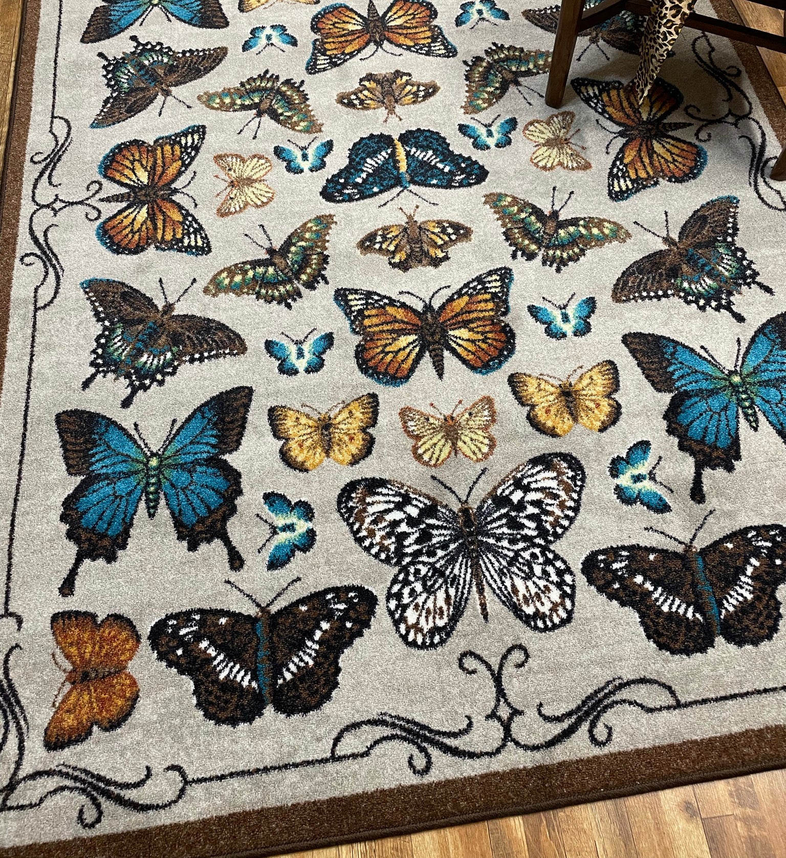 Detail of butterfly game room rug near wooden bench with leopard blanket—highlighting bold color and fine illustration details.