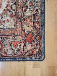 Load image into Gallery viewer, Corner view of The Ravencourt Rug highlighting its intricate border and worn-in look of parchment and wine-red hues.