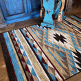 Load image into Gallery viewer, Room scene with the Trail of Glass rug beneath a rustic bench holding a saddle, showcasing the tribal diamond pattern in warm turquoise, gold, and rust tones