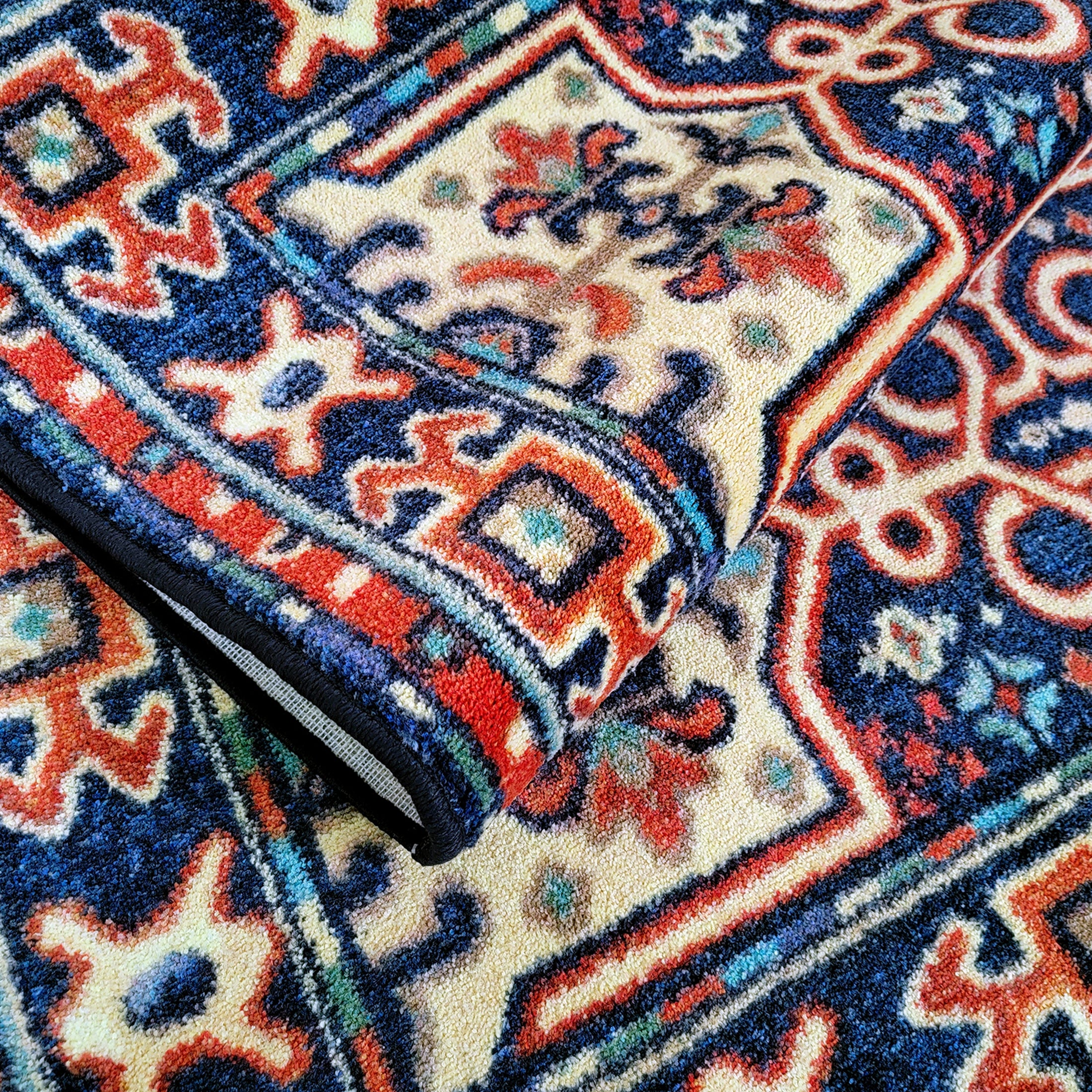 The Alchemist Rug folded to show its flexibility and rich woven texture in deep blues and fiery reds