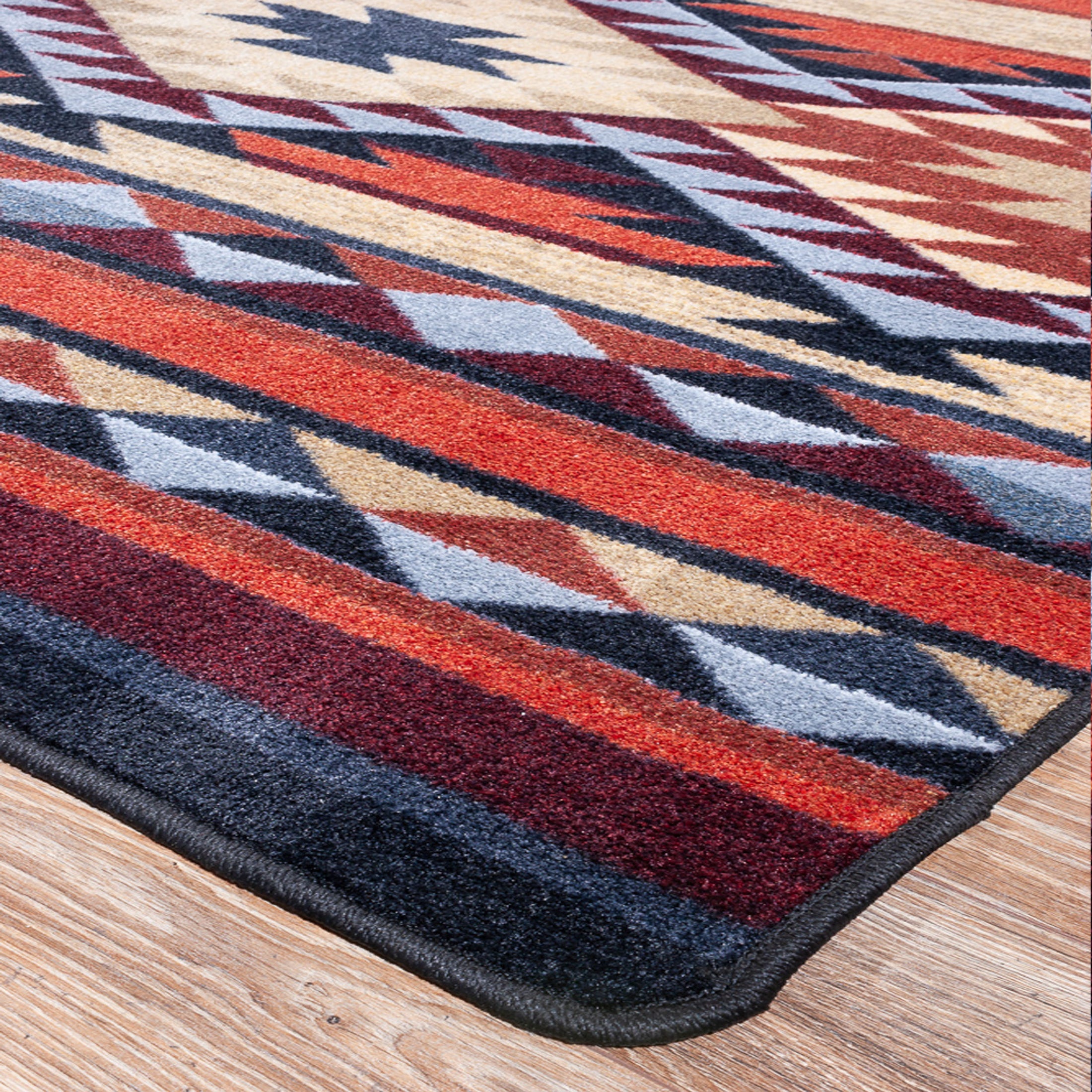 Close-up of the Ashspire Ridge rug corner showing clean edging and sharp tribal diamond pattern in rust, navy, and gold tones