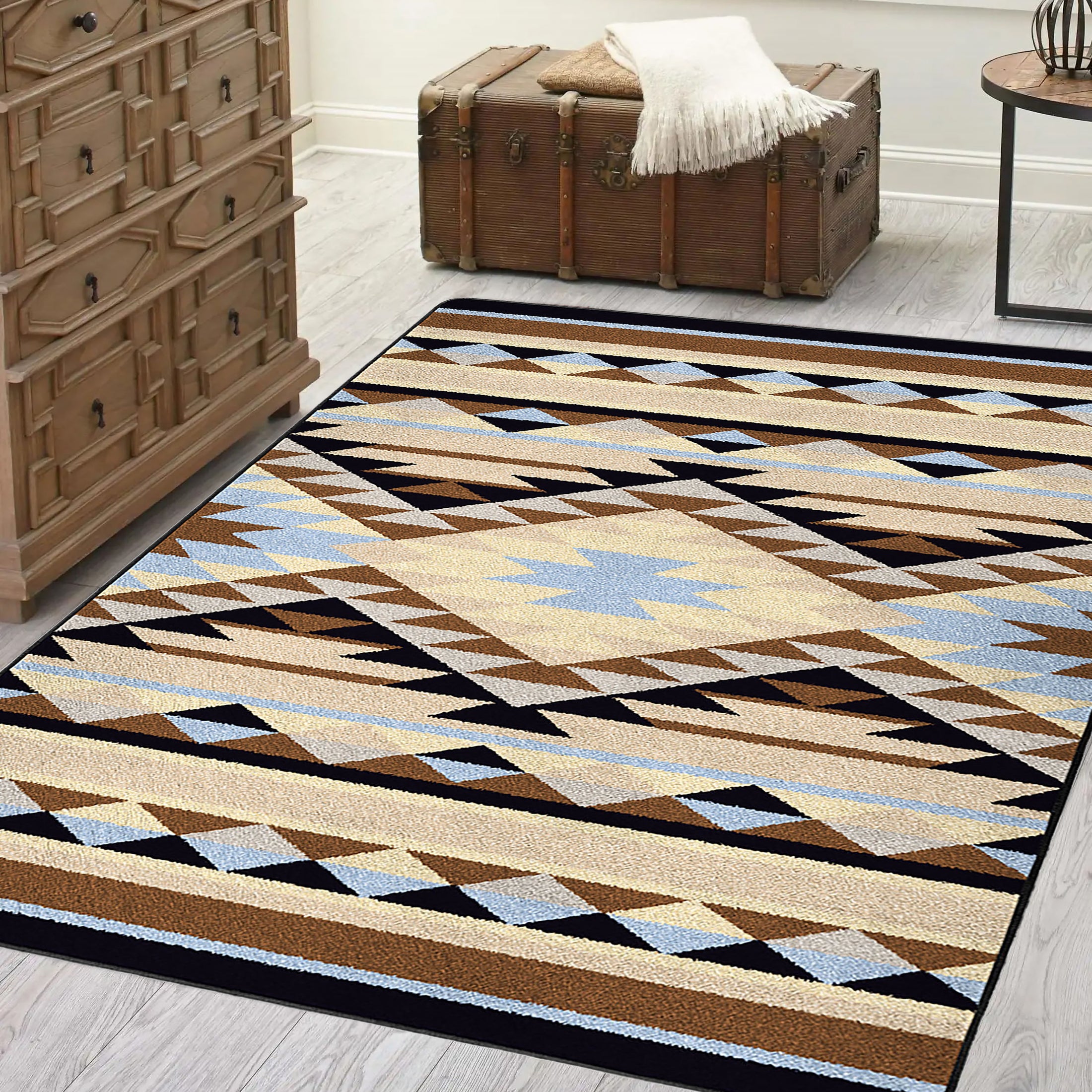 Room scene with The Desert’s Oracle rug placed beneath a vintage trunk and dresser, showcasing the sun-faded tribal diamond pattern in sand and sky blue tones