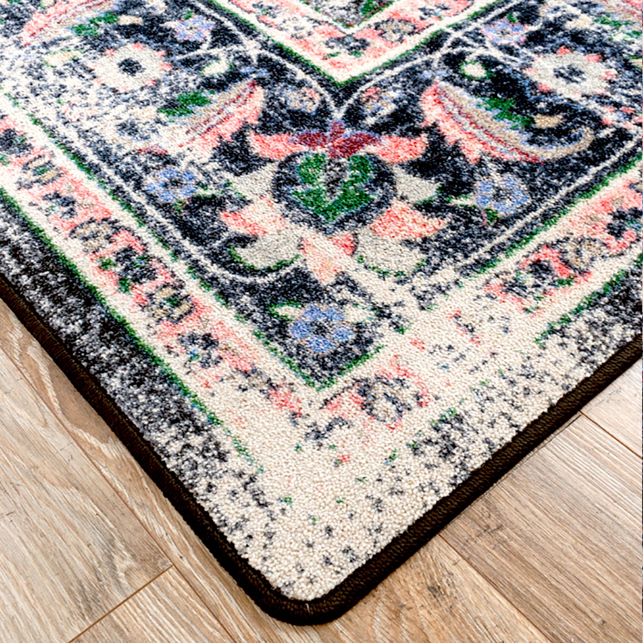 Corner detail of The Floromancer’s Medallion rug showing pink floral motifs against a distressed black background