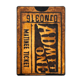 Golden Reel rug shown flat, featuring a vintage theater ticket design in warm bronze tones