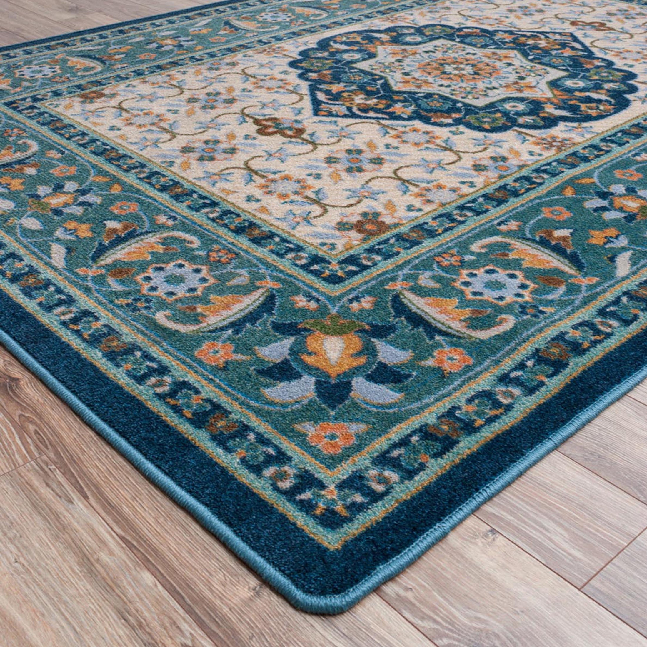 Close-up of The Navigator’s Medallion rug corner showing detailed scrollwork in teal and gold, clean edging, and rich texture on a parchment-toned background

