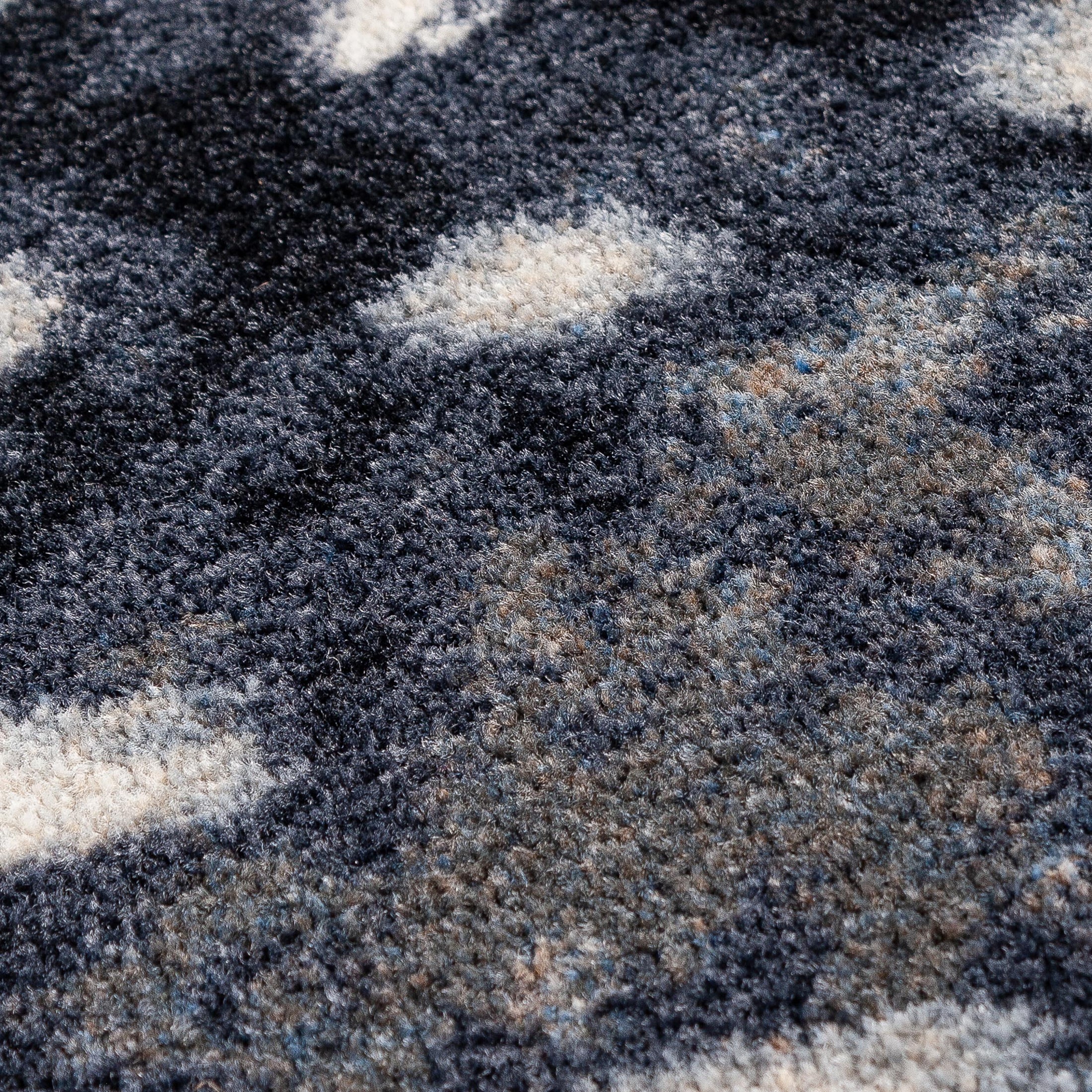 Extreme close-up of Nocturna’s Hide rug yarn and weave, highlighting the soft, high-density texture and contrast between dark and light fibers