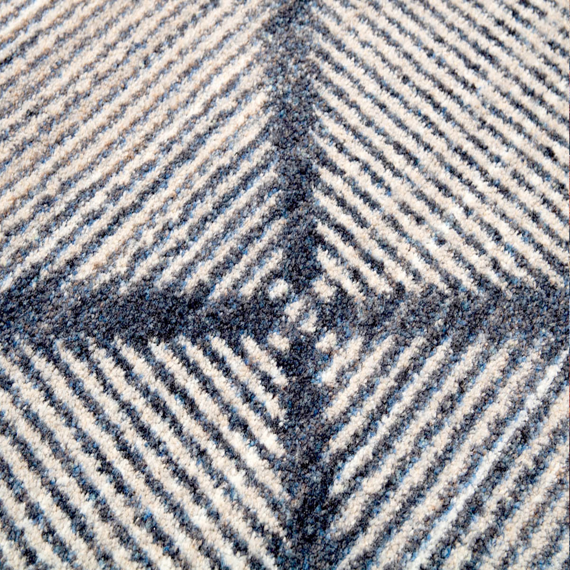 Extreme close-up of the Prismspire rug yarn texture, highlighting the tight weave and fade detailing in navy and cream tones

