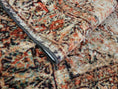 Load image into Gallery viewer, The Ravencourt Rug folded to reveal its durable construction and richly layered design of reds and ash black.
