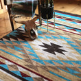 Load image into Gallery viewer, Staged room with the Trail of Glass rug beneath a chair and decorative ram skull, highlighting the geometric design and sun-worn desert color palette


