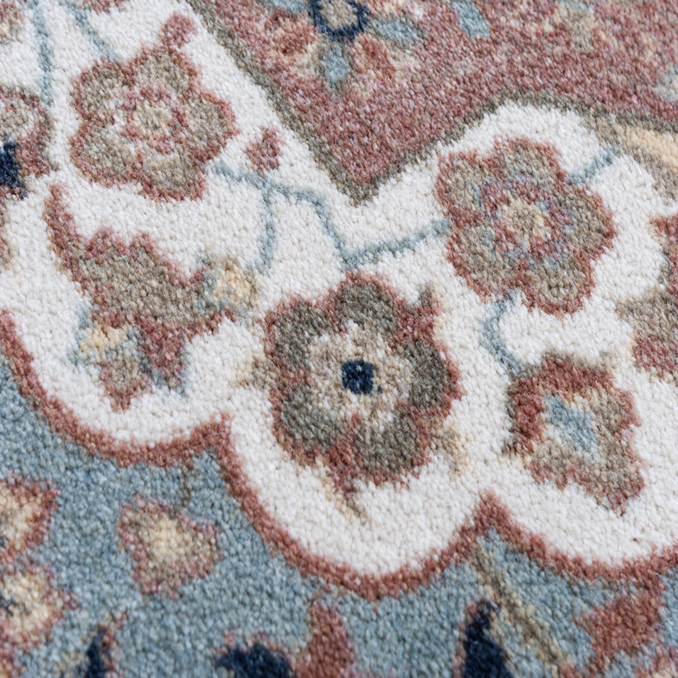 Extreme close-up of The Weaver’s Medallion rug yarn texture, displaying the fine EnduraStran weave in muted sage, parchment, and rose tones