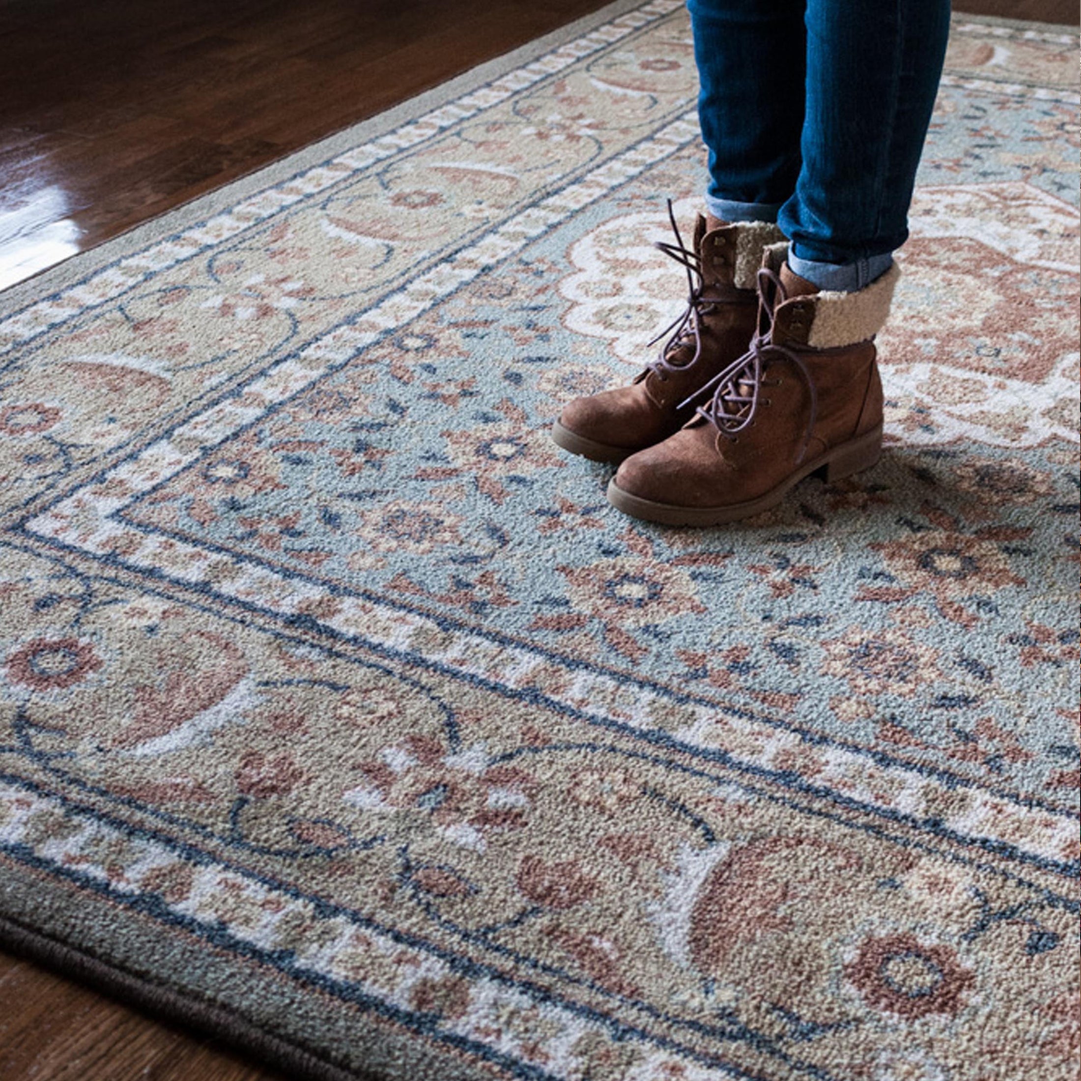 Close-up of a girl’s feet standing on The Weaver’s Medallion rug, highlighting the texture and gentle hues of sage, blue, and rose

