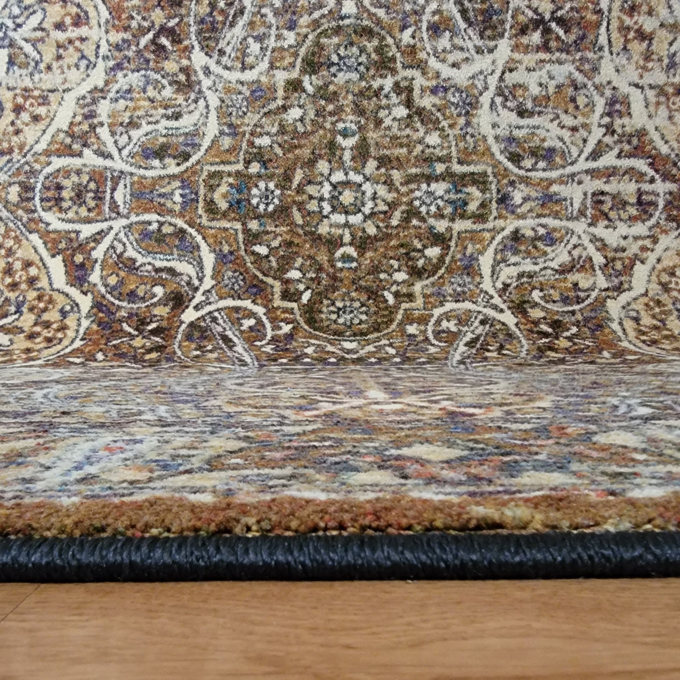 Edge of The Wildroot Rug showing faded ivory patterning and finished binding