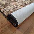 Load image into Gallery viewer, Rolled-up rug with a textured surface on a wooden floor
